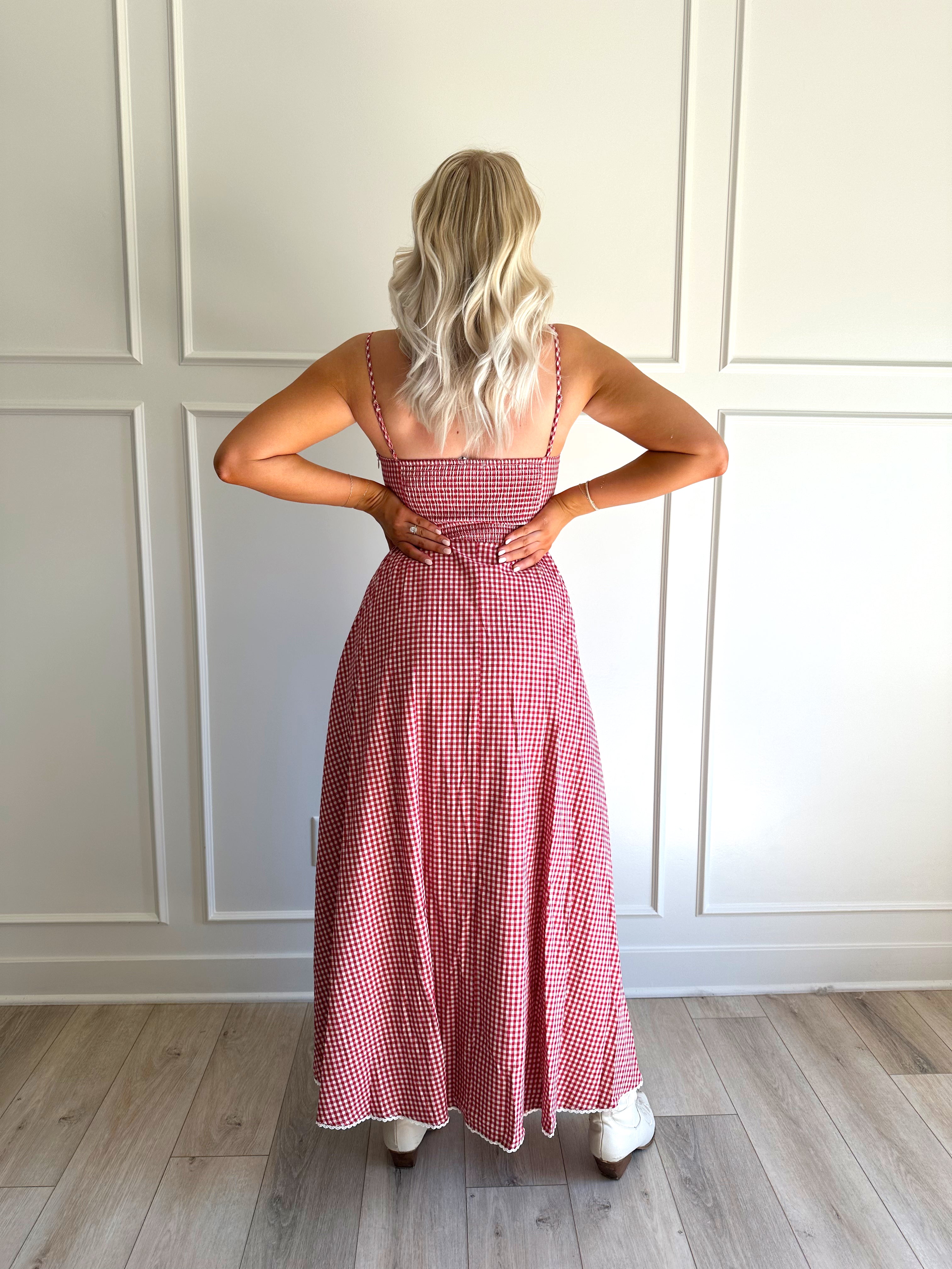 Woman wearing red gingham maxi dress with button detailing. 