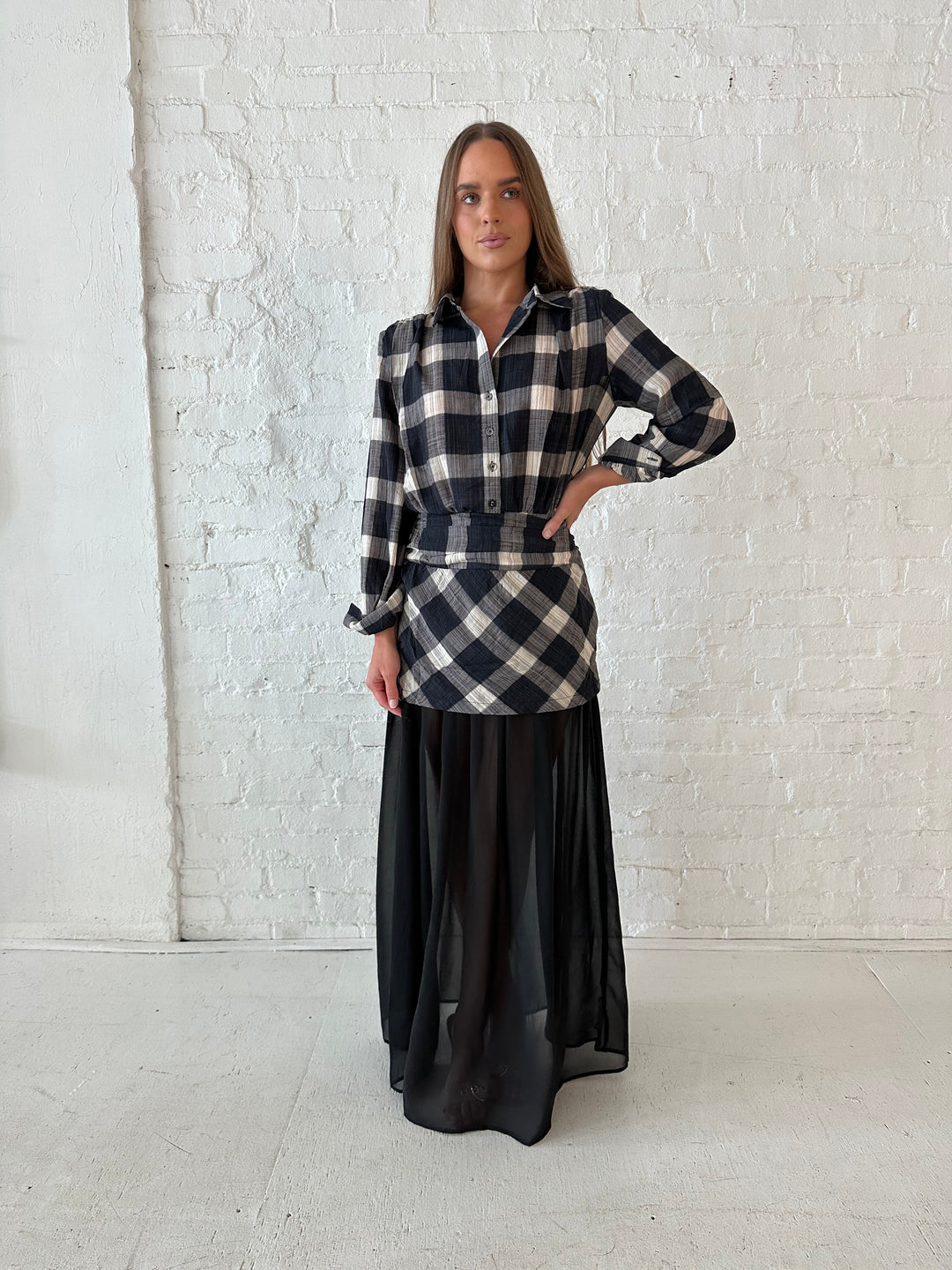 Woman wearing black checkered maxi dress with sheer maxi skirt bottom.
