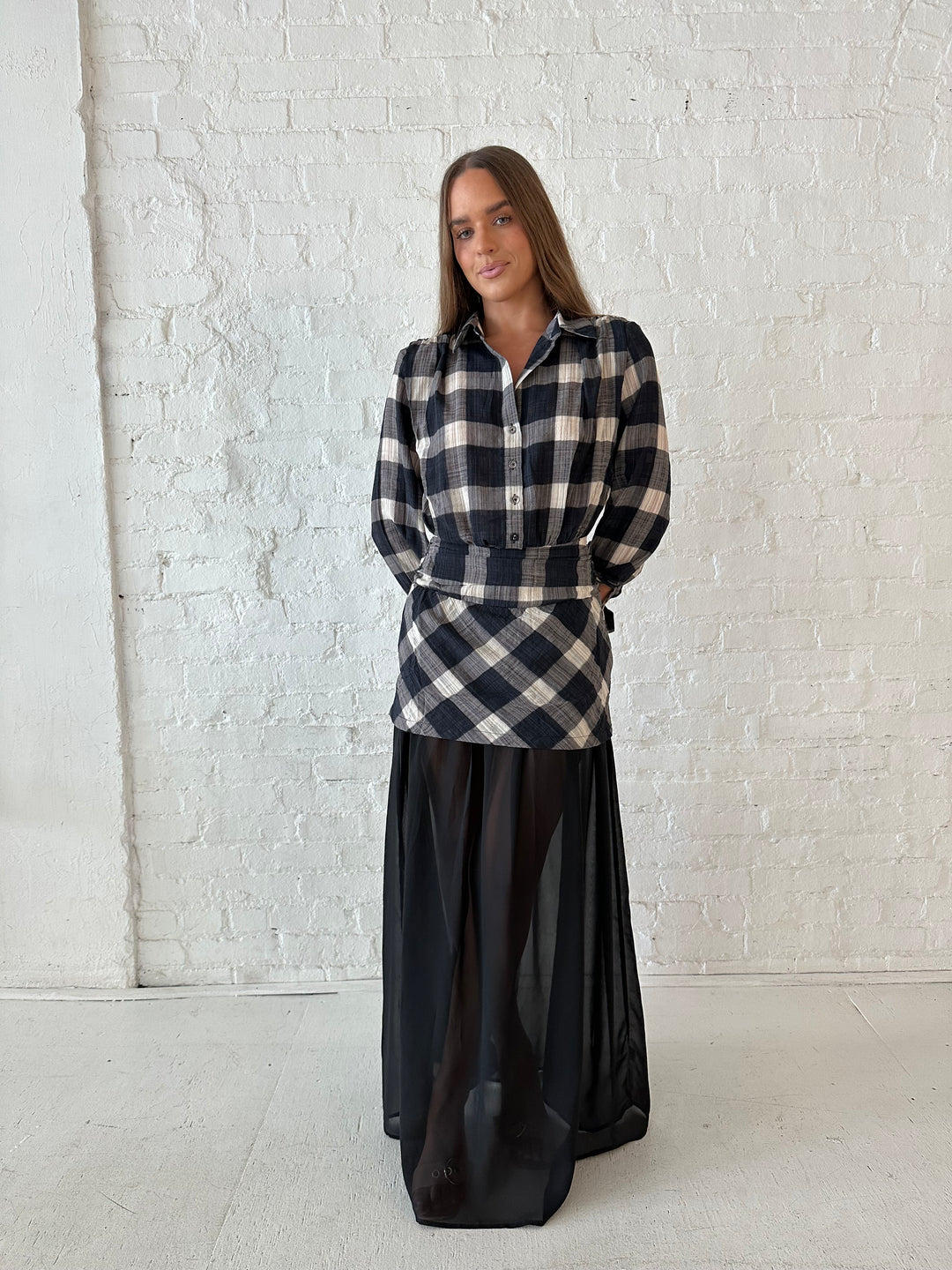 Woman wearing black checkered maxi dress with sheer maxi skirt bottom.