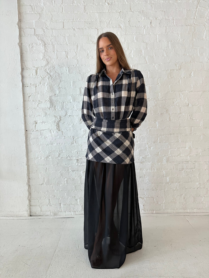 Woman wearing black checkered maxi dress with sheer maxi skirt bottom.