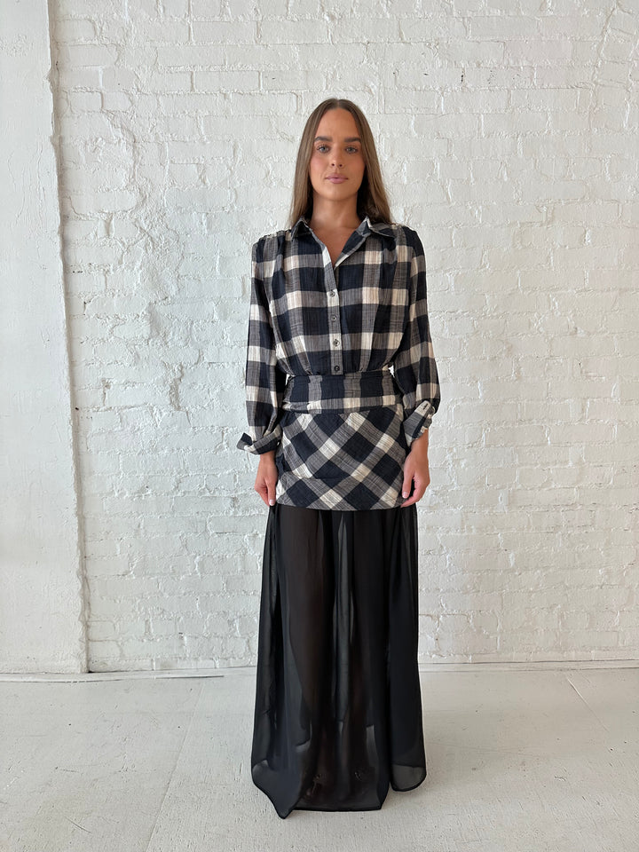Woman wearing black checkered maxi dress with sheer maxi skirt bottom.