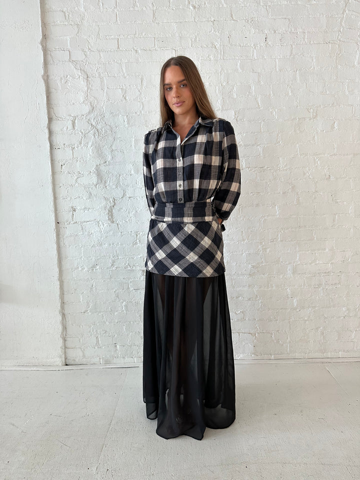 Woman wearing black checkered maxi dress with sheer maxi skirt bottom.