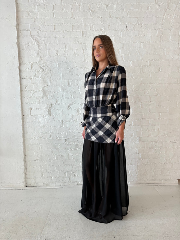 Woman wearing black checkered maxi dress with sheer maxi skirt bottom.