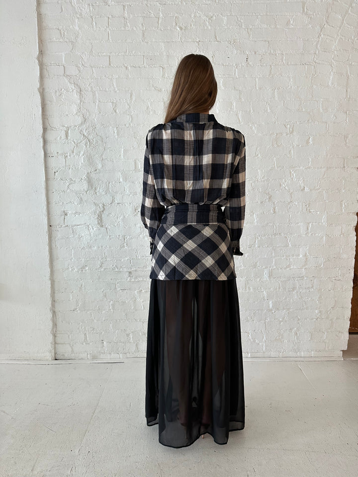 Woman wearing black checkered maxi dress with sheer maxi skirt bottom.