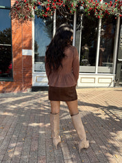 Woman wearing brown peplum style sweater top with button closure. 