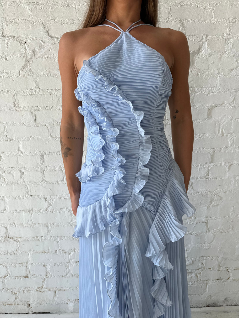 Woman wearing blue chiffon textured midi dress with halter neckline.