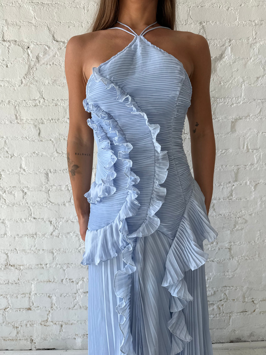 Woman wearing blue chiffon textured midi dress with halter neckline.