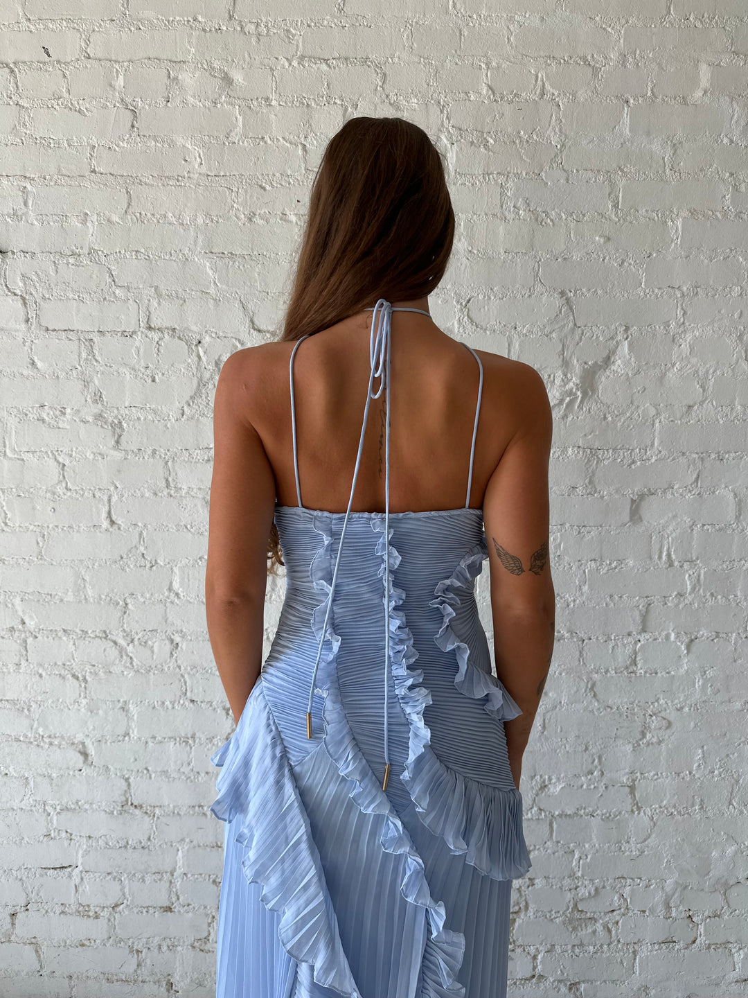 Woman wearing blue chiffon textured midi dress with halter neckline.