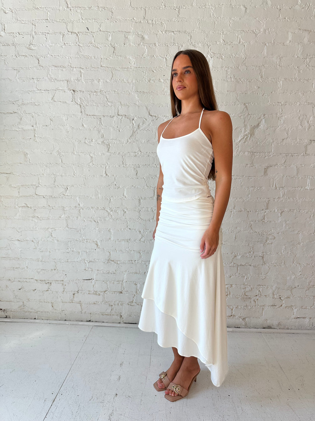 Woman wearing white two piece set with layered midi skirt, and halter top. 