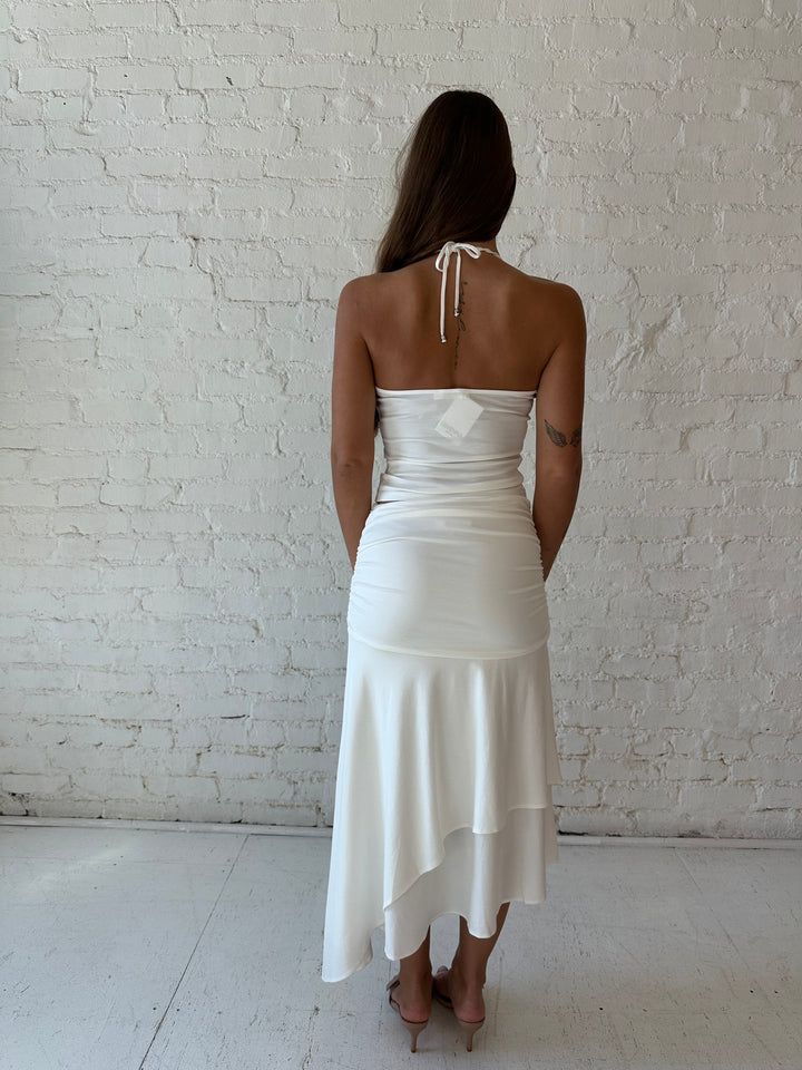 Woman wearing white two piece set with layered midi skirt, and halter top. 