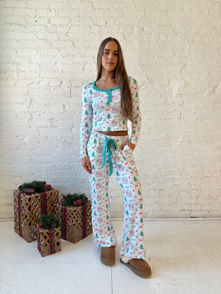 Woman wearing vintage Christmas postage pattern pajama set. 
