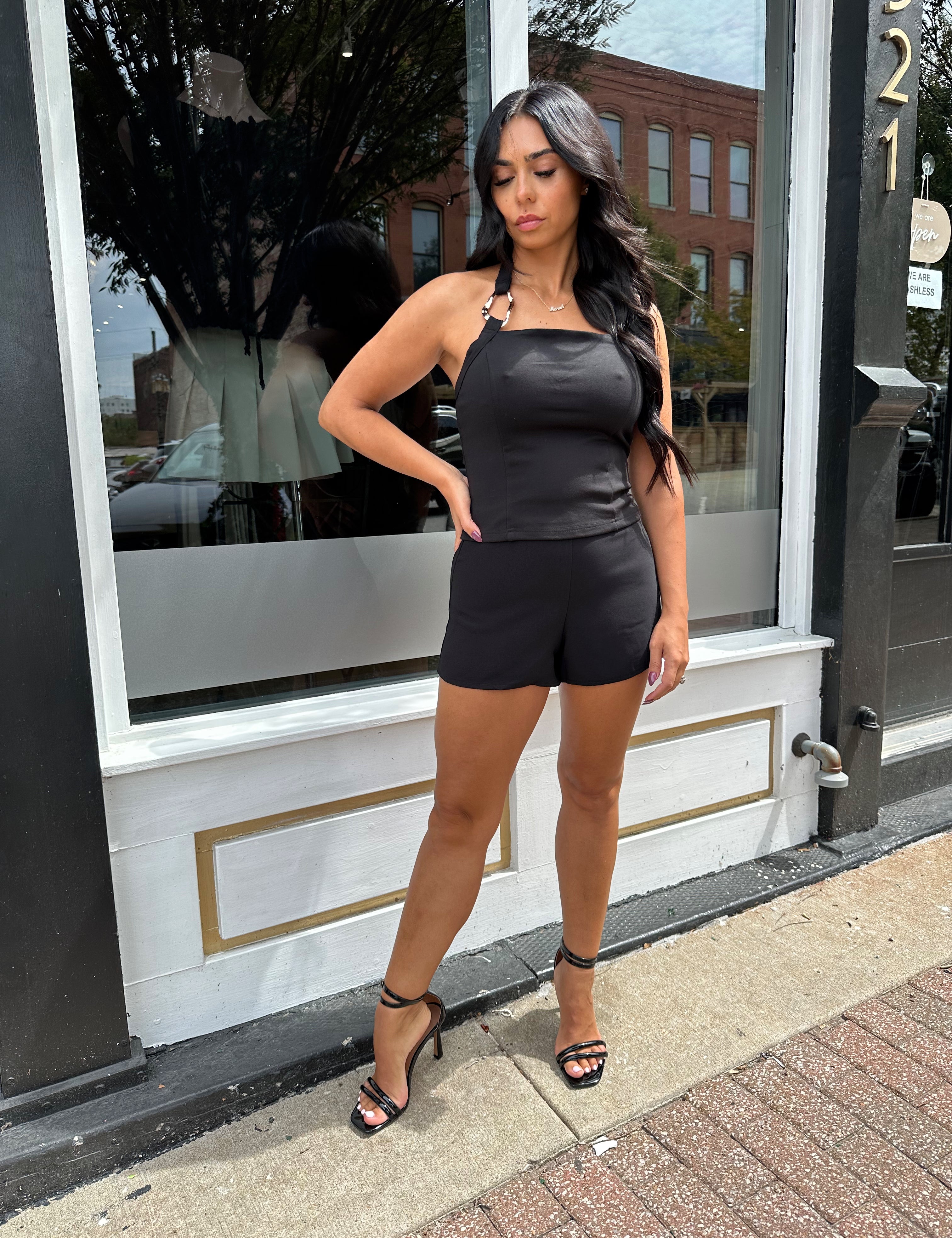 Woman wearing black halter top with chain link detail. 