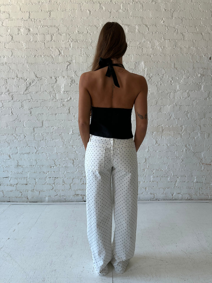 Woman wearing black linen halter top with white polka dot low rise jeans. 