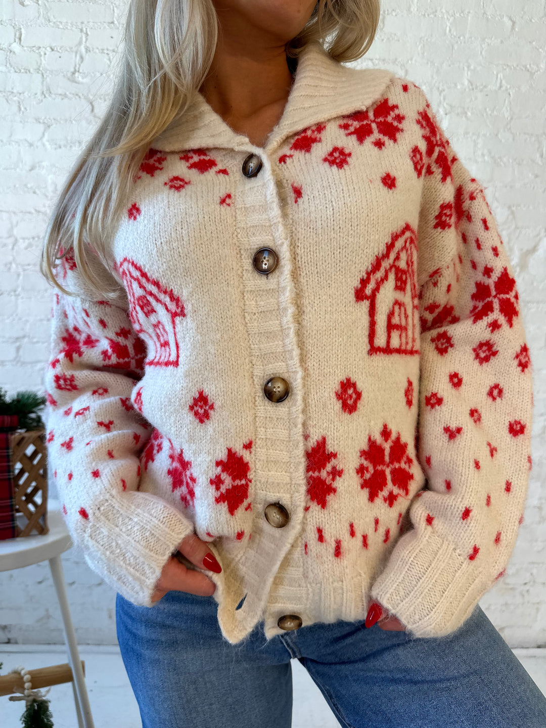 Woman wearing cream button down cardigan with red Christmas pattern all over.
