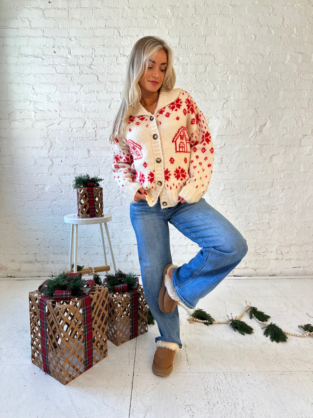 Woman wearing cream button down cardigan with red Christmas pattern all over.