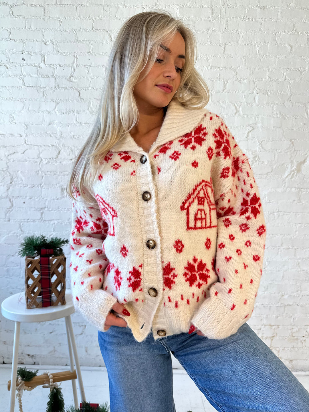 Woman wearing cream button down cardigan with red Christmas pattern all over.