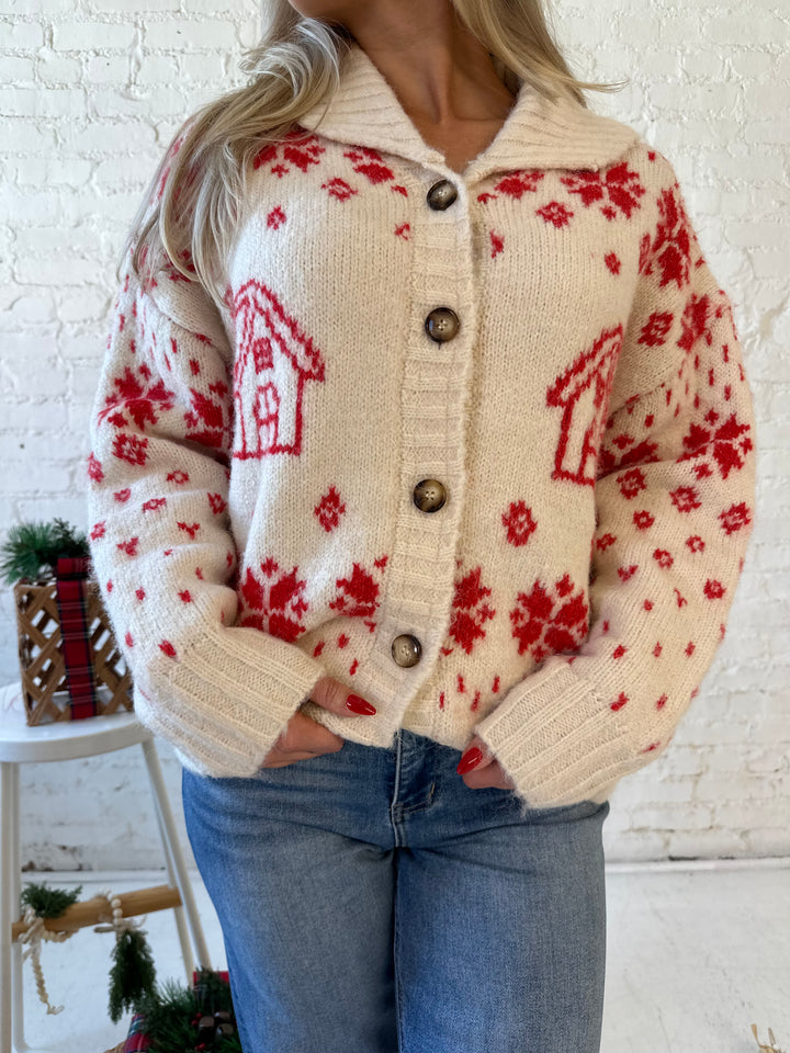 Woman wearing cream button down cardigan with red Christmas pattern all over.