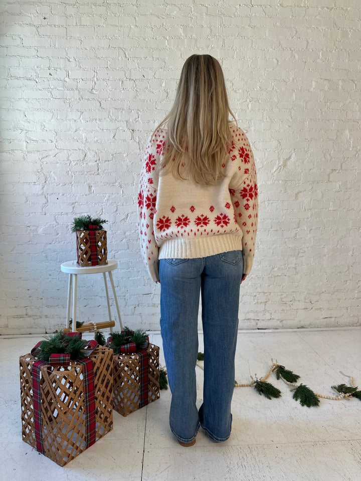 Woman wearing cream button down cardigan with red Christmas pattern all over.