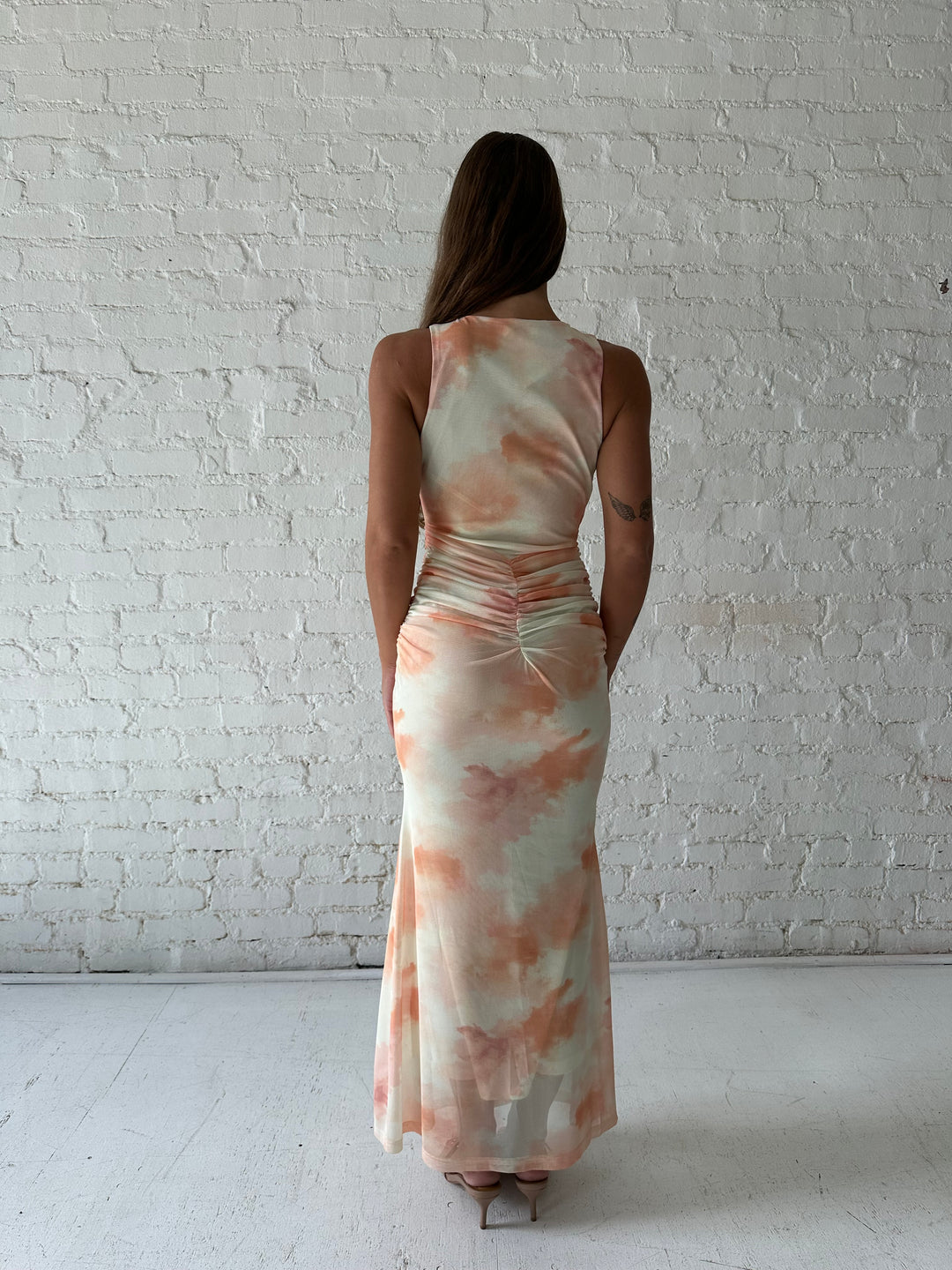 Woman wearing yellow watercolor maxi dress with high neckline, and ruched side detailing. 
