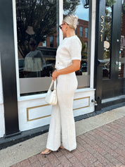 Ivory bouclé two piece set with gold button closure and wide leg pant. 