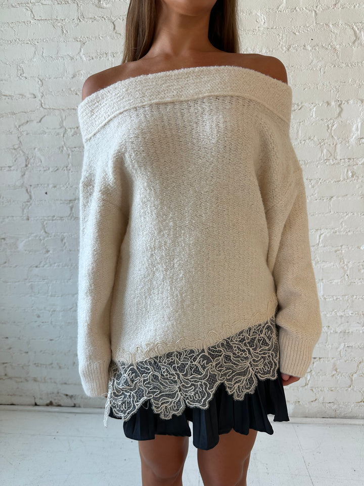 Woman wearing cream off the shoulder sweater with lace trim hem and charcoal pleated mini skort. 
