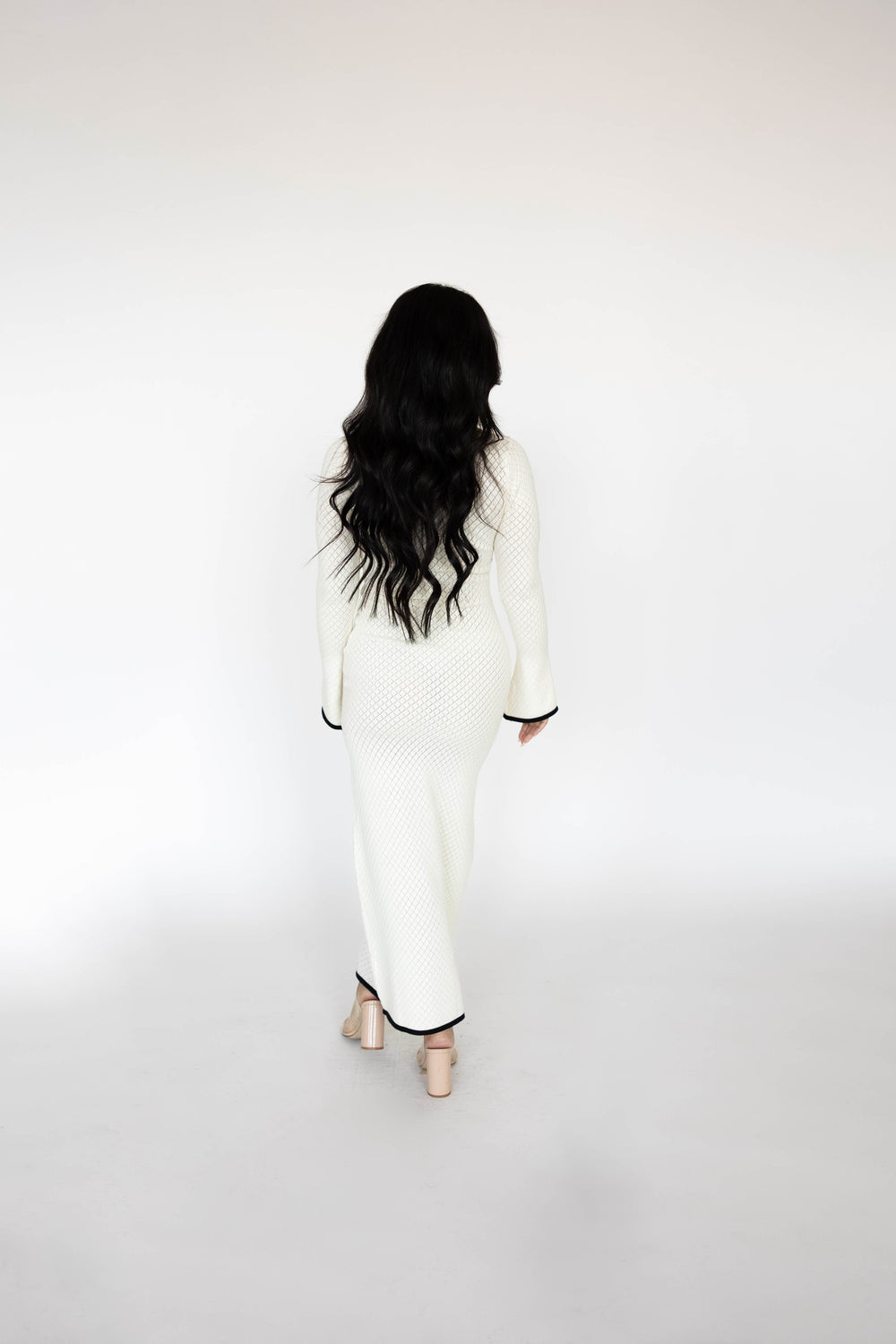 Woman wearing ivory long sleeve knit maxi dress with black contrast trim.
