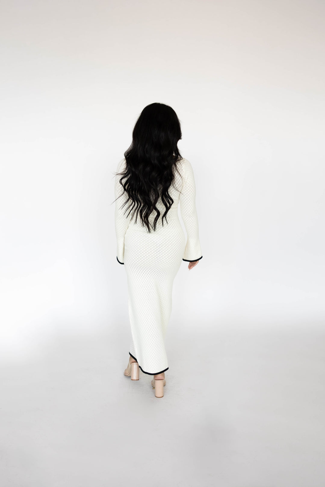 Woman wearing ivory long sleeve knit maxi dress with black contrast trim.