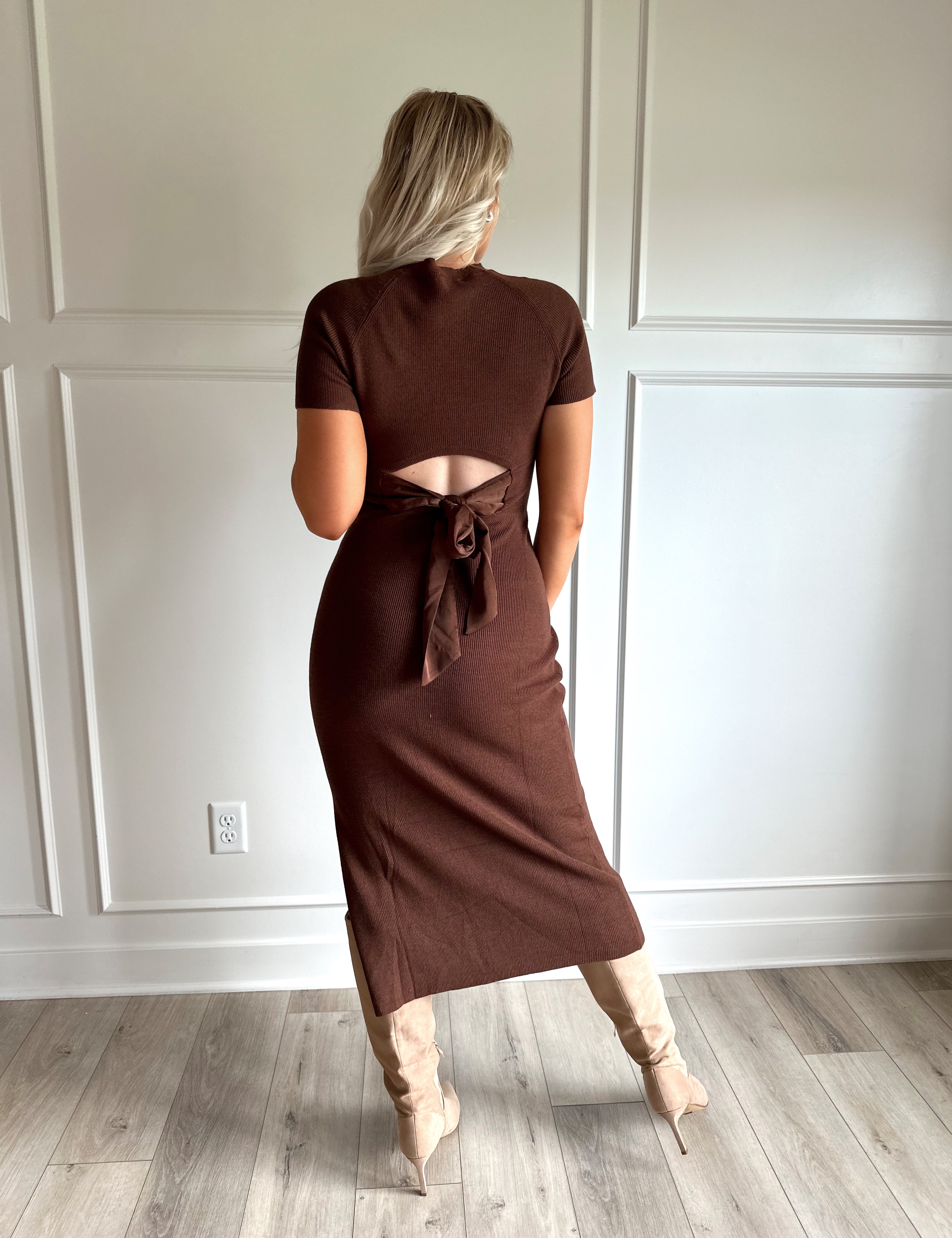 Woman wearing brown ribbed short sleeve midi dress with cutout back and tie detail.