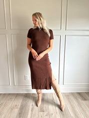 Woman wearing brown ribbed short sleeve midi dress with cutout back and tie detail.