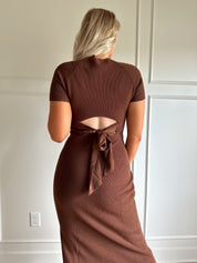 Woman wearing brown ribbed short sleeve midi dress with cutout back and tie detail.