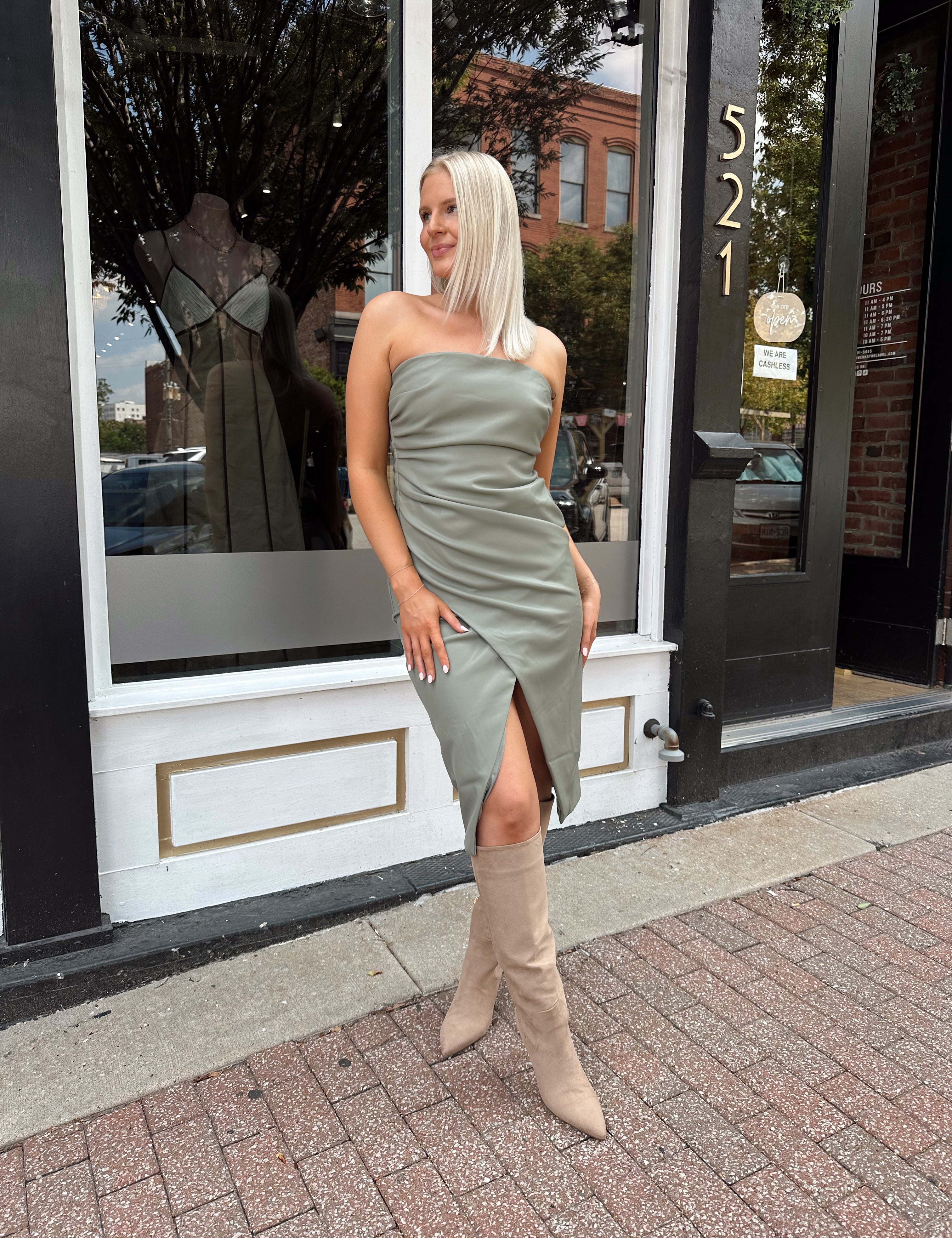 Woman wearing an olive green vegan leather midi dress with drapery detail.