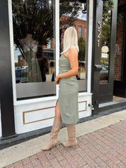 Woman wearing an olive green vegan leather midi dress with drapery detail.