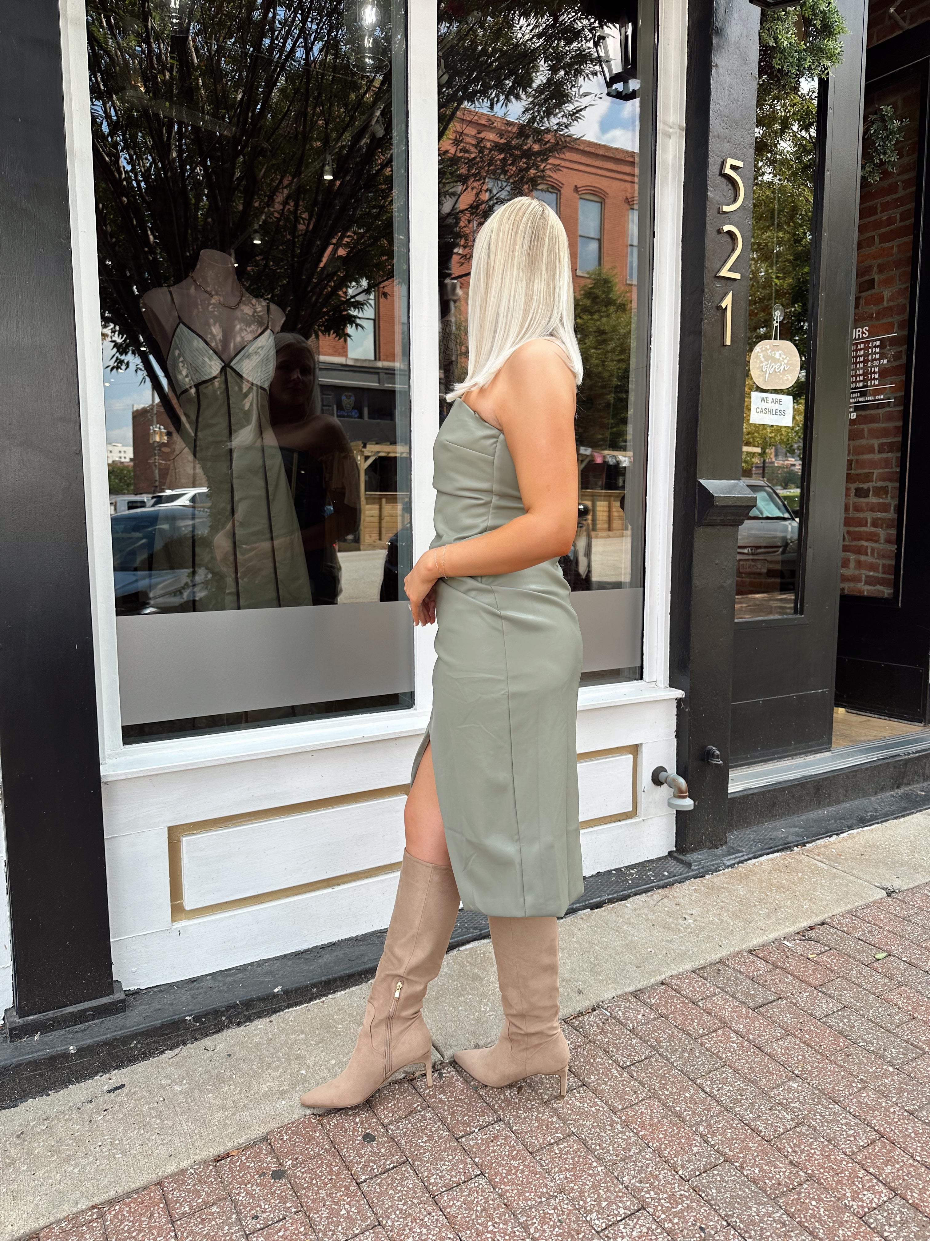Woman wearing an olive green vegan leather midi dress with drapery detail.
