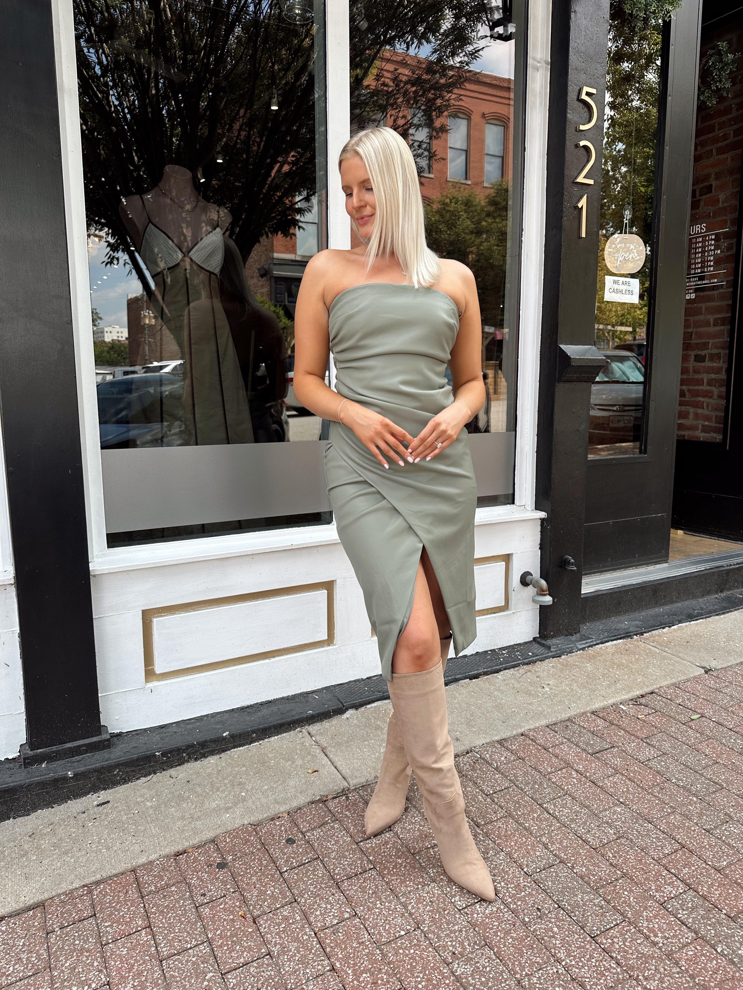 Woman wearing an olive green vegan leather midi dress with drapery detail.