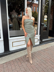 Woman wearing an olive green vegan leather midi dress with drapery detail.