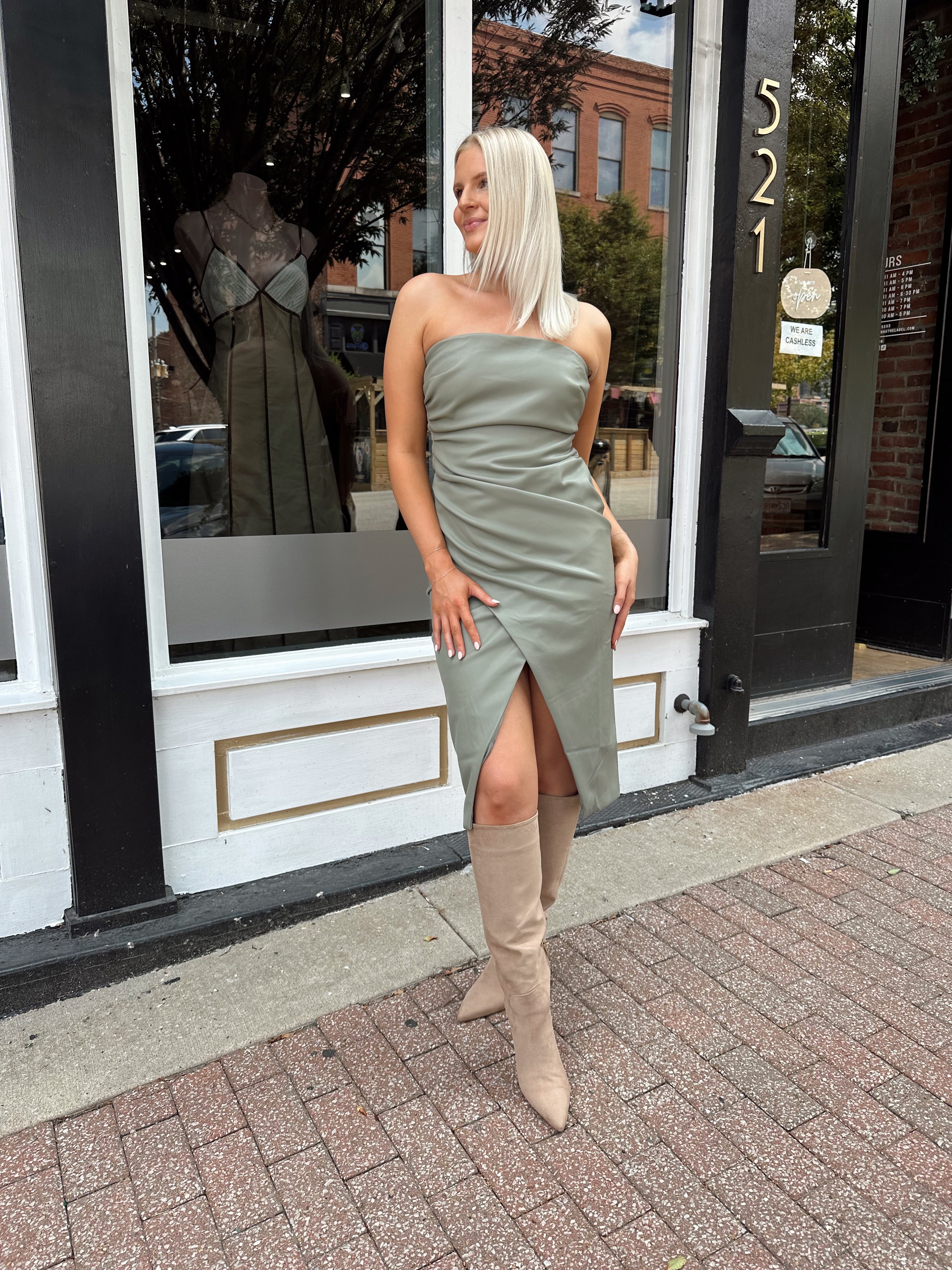 Woman wearing an olive green vegan leather midi dress with drapery detail.