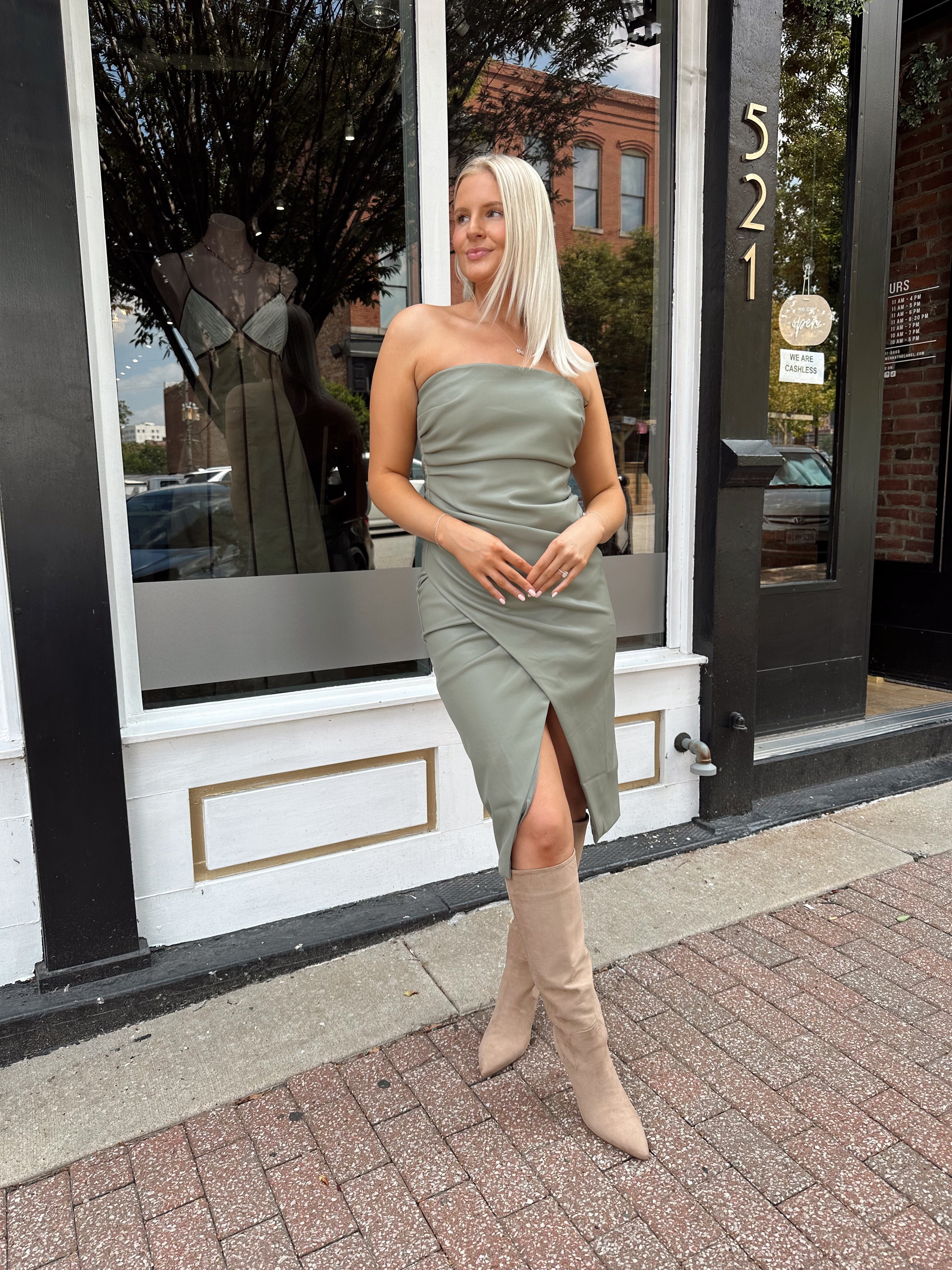 Woman wearing an olive green vegan leather midi dress with drapery detail.