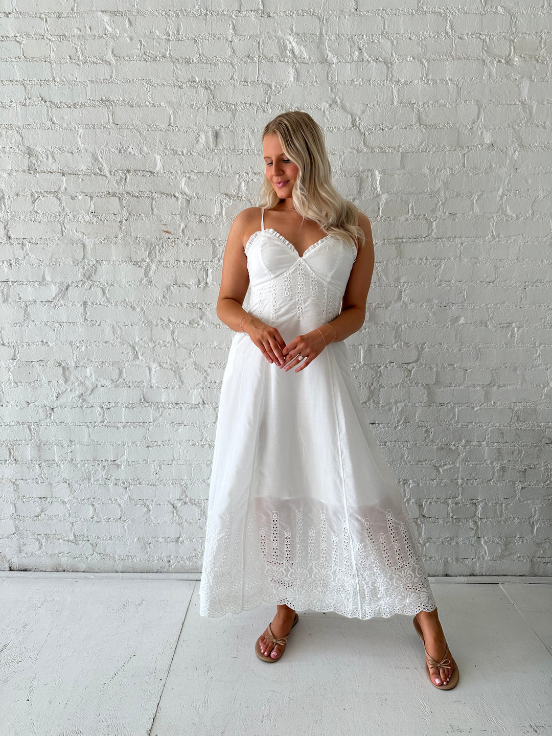 Woman wearing white eyelet maxi dress with open back, and functional pockets. 