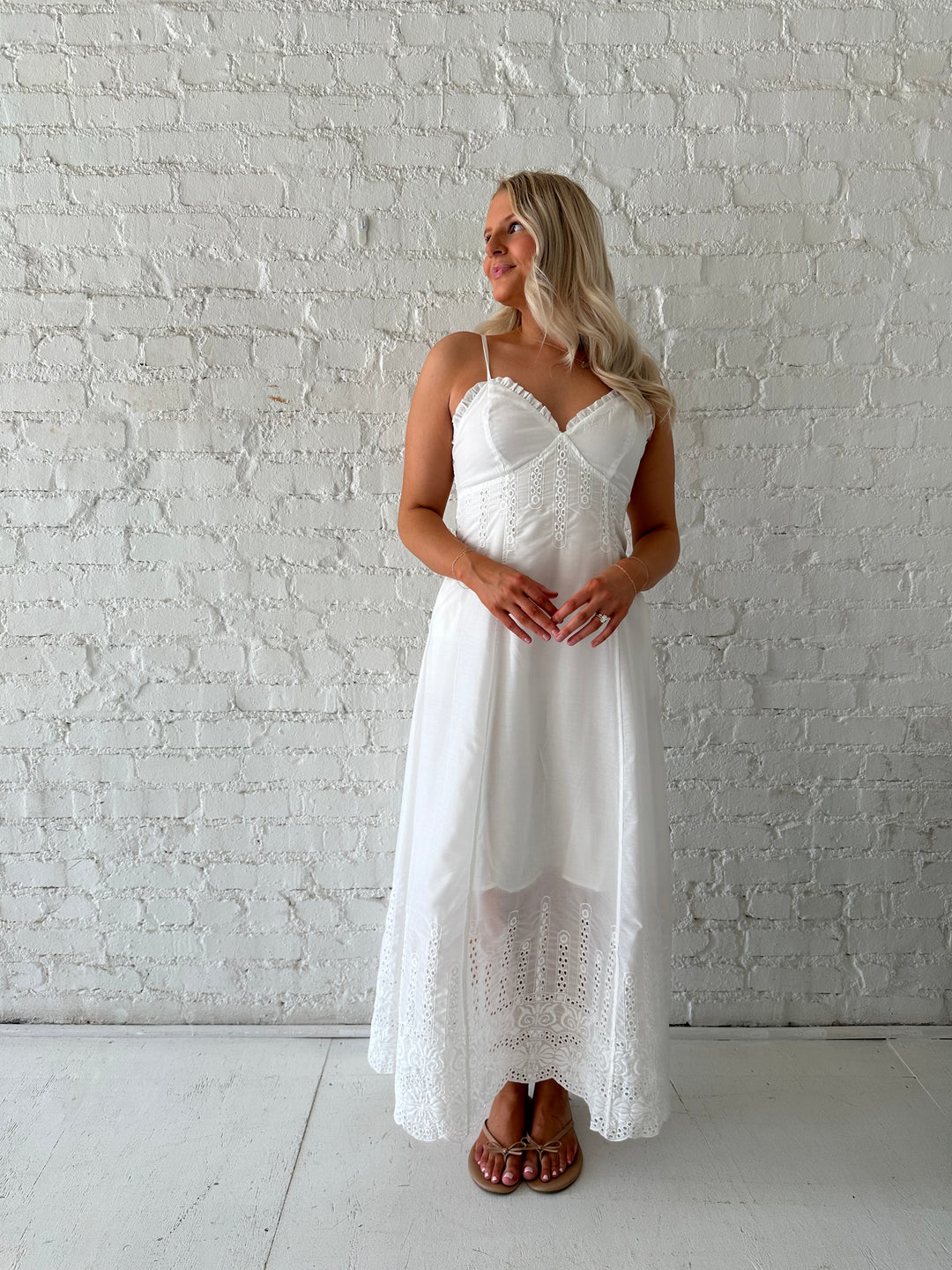 Woman wearing white eyelet maxi dress with open back, and functional pockets. 