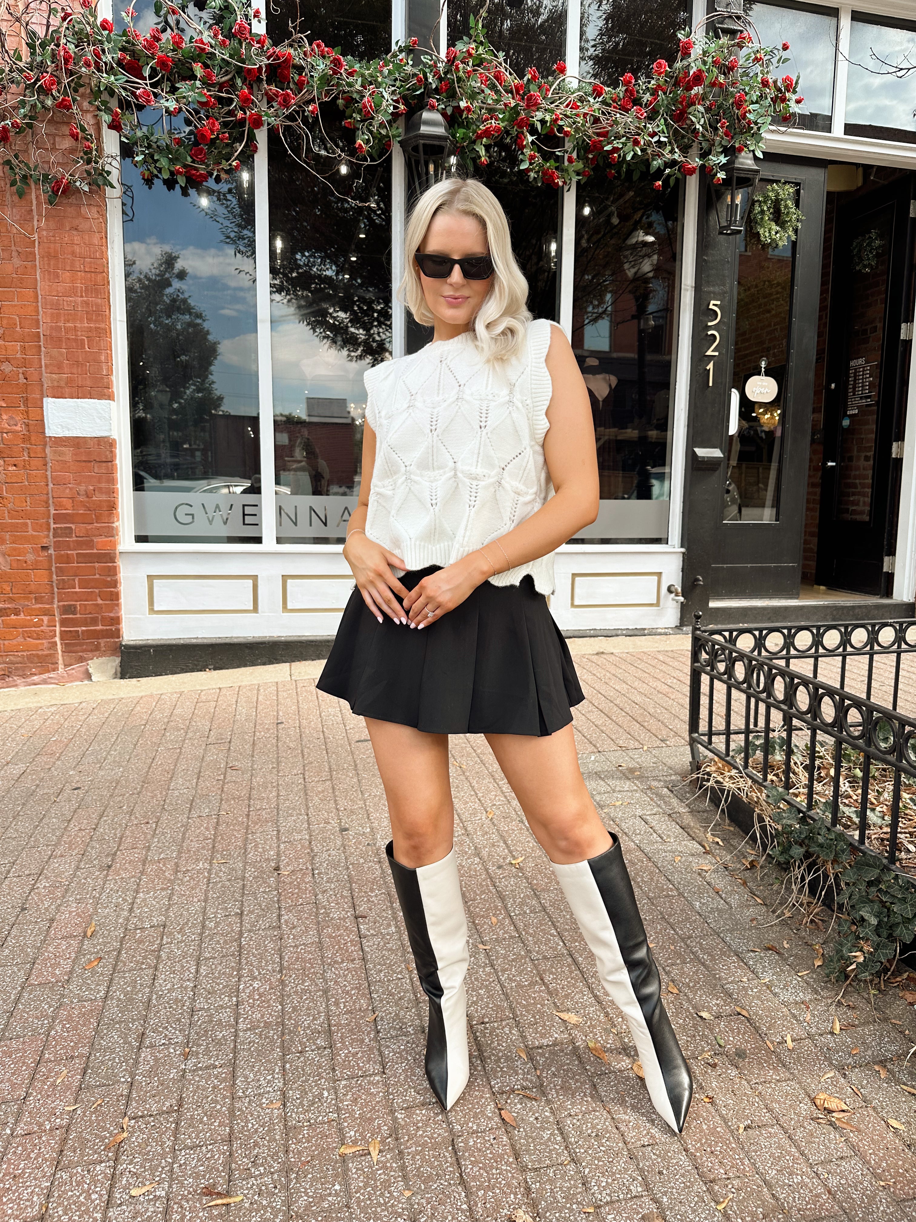 Woman wearing cream cable knit sweater with black bow detail