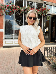 Woman wearing cream cable knit sweater with black bow detail