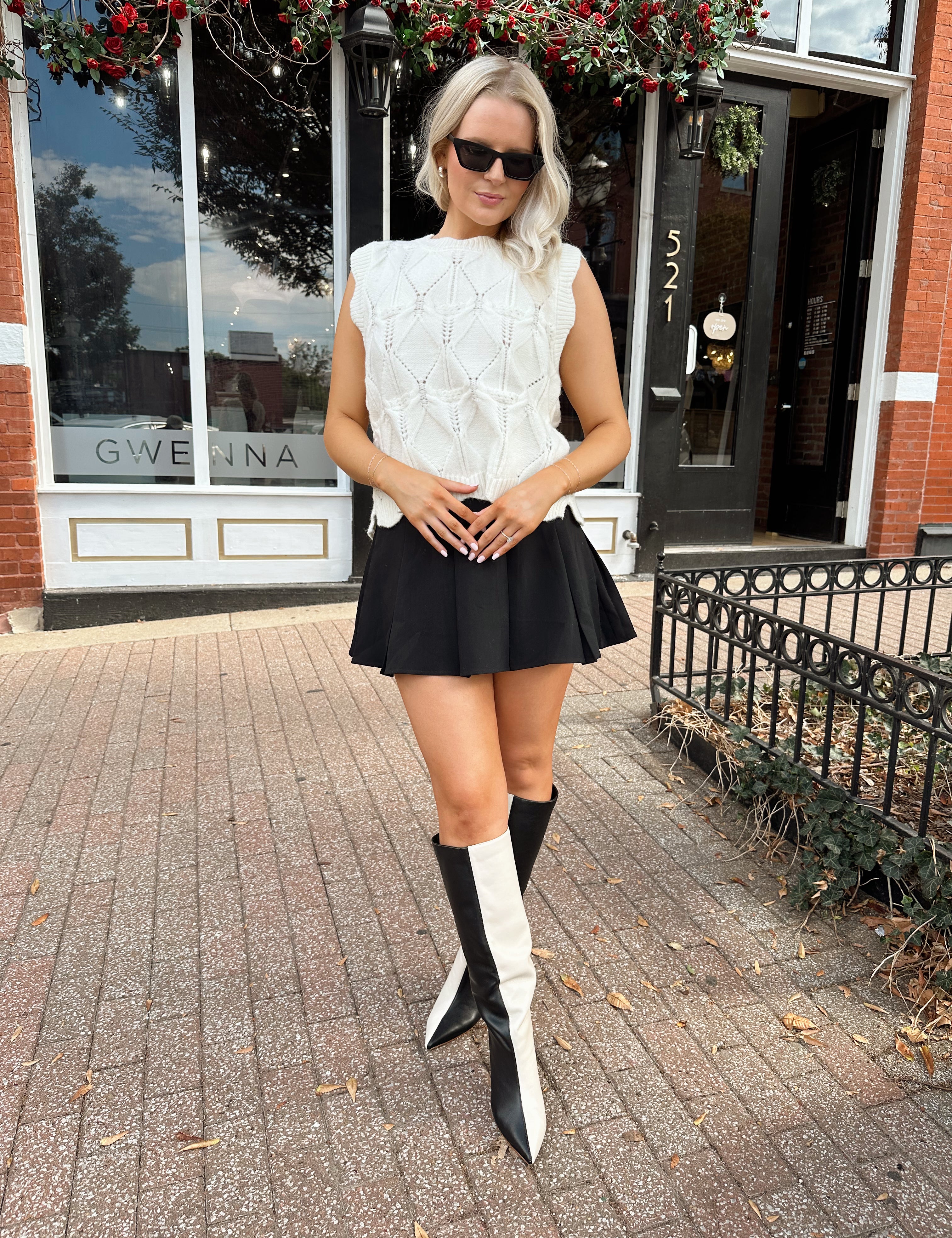 Woman wearing cream cable knit sweater with black bow detail