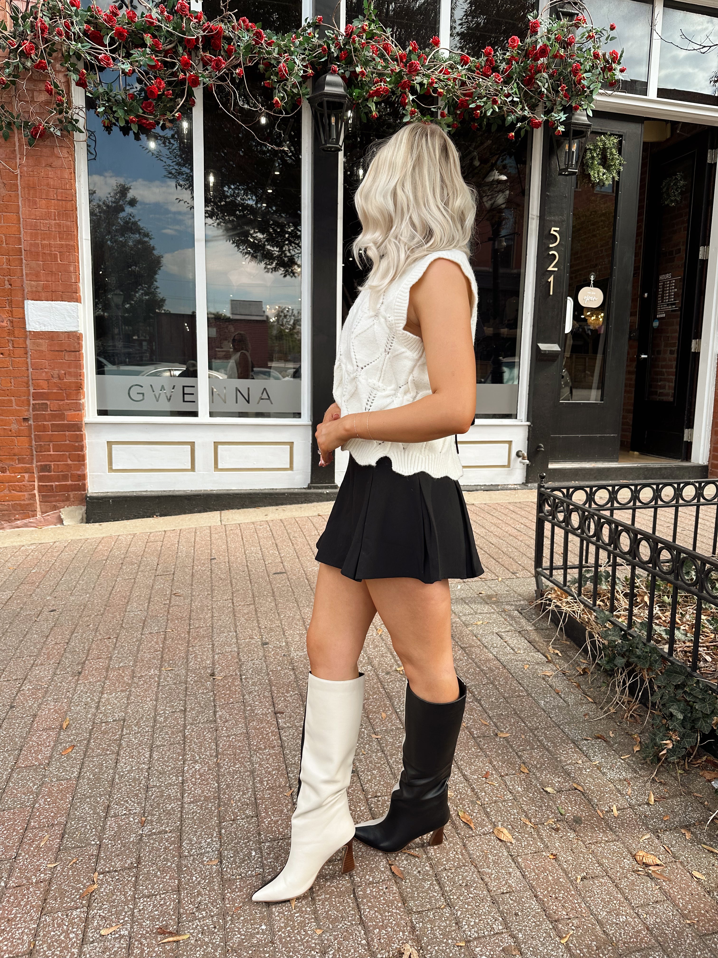 Woman wearing cream cable knit sweater with black bow detail