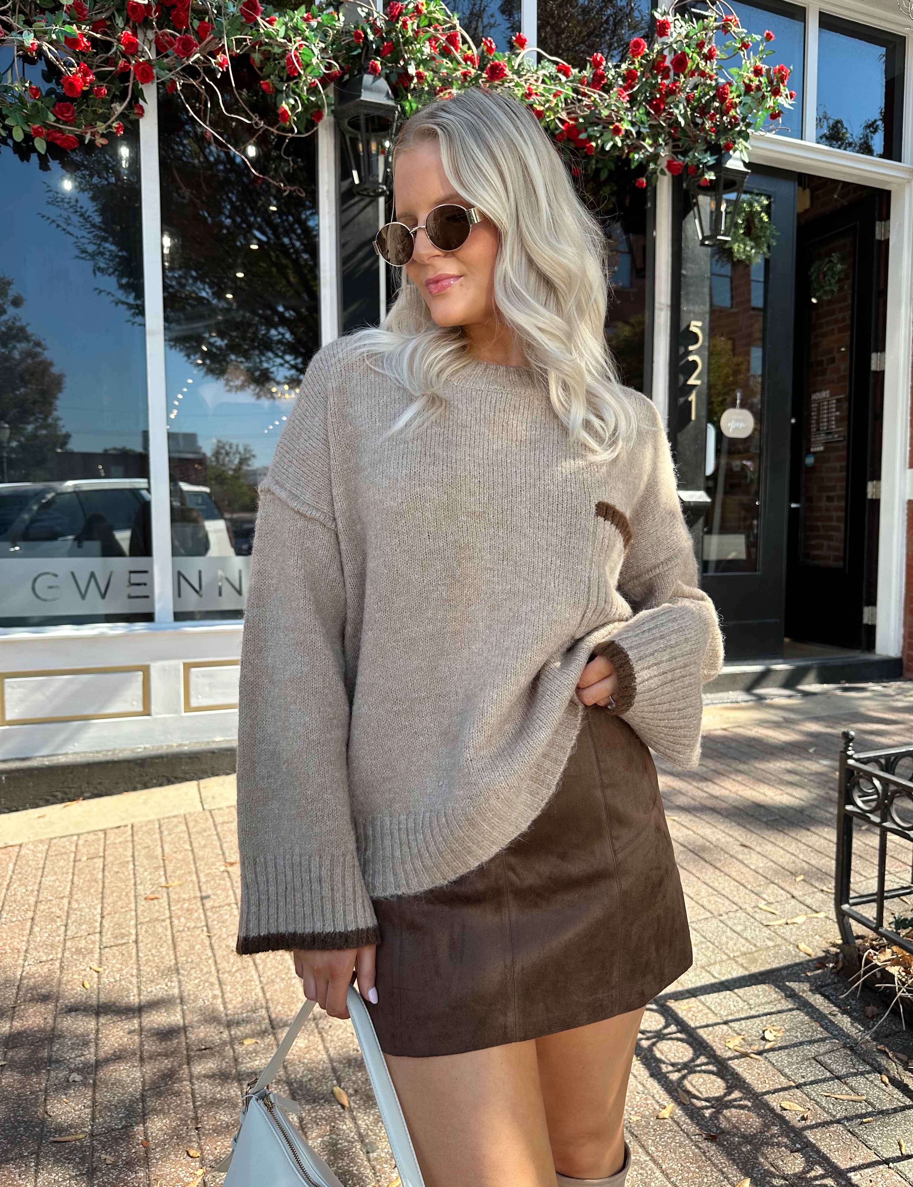 Woman wearing brown suede mini skirt with taupe oversized sweater.