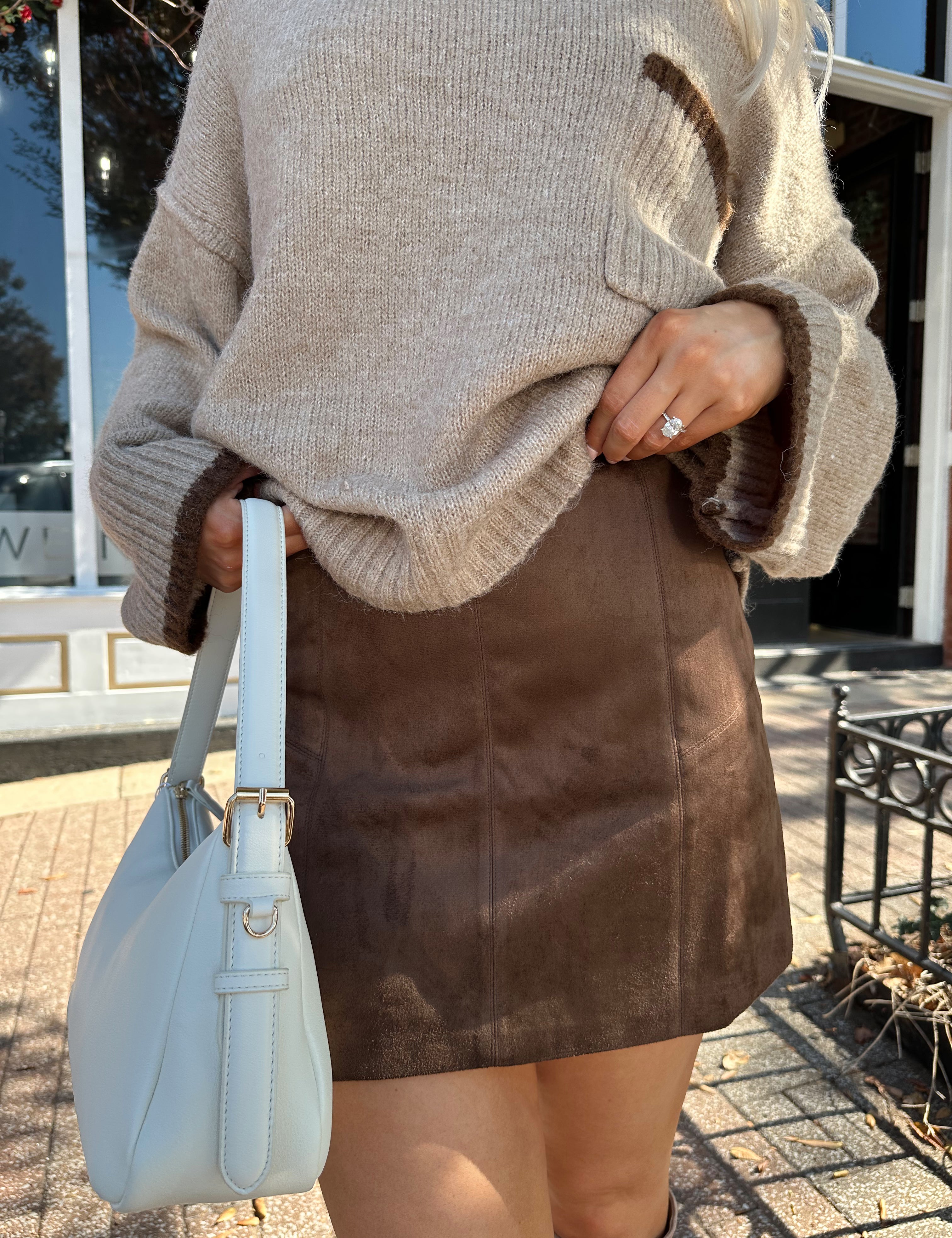 Woman wearing brown suede mini skirt with taupe oversized sweater.