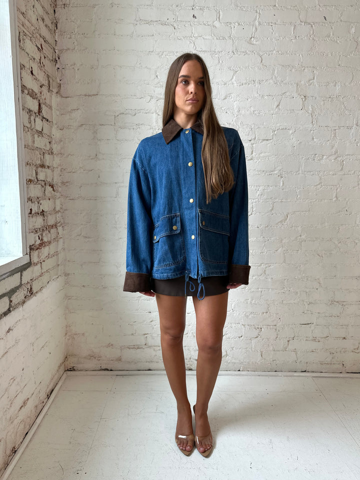 Woman wearing dark wash denim bomber jacket with brown corduroy collar and wrist cuffs.