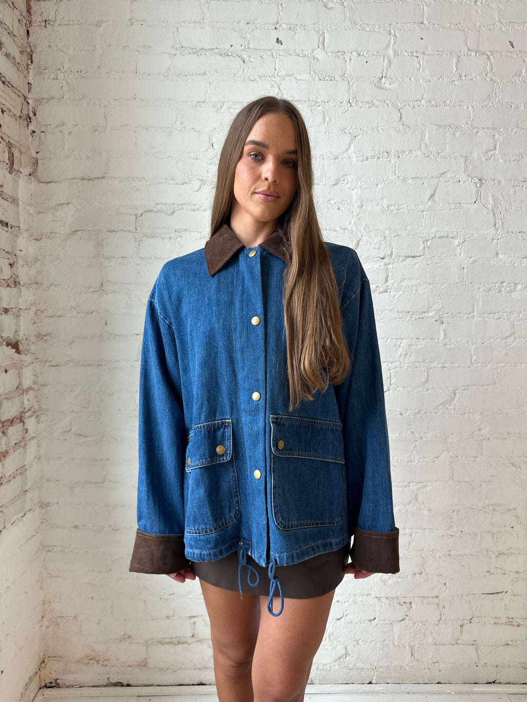 Woman wearing dark wash denim bomber jacket with brown corduroy collar and wrist cuffs.