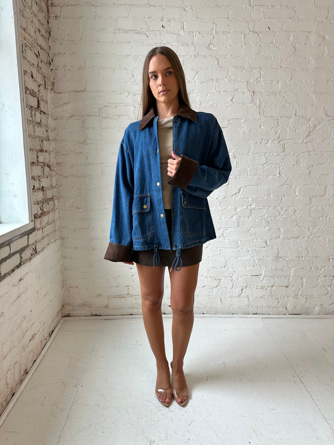 Woman wearing dark wash denim bomber jacket with brown corduroy collar and wrist cuffs.