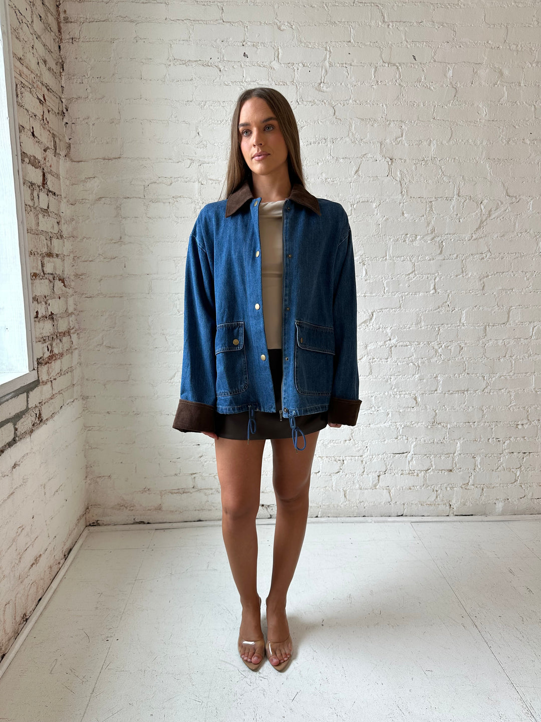 Woman wearing dark wash denim bomber jacket with brown corduroy collar and wrist cuffs.