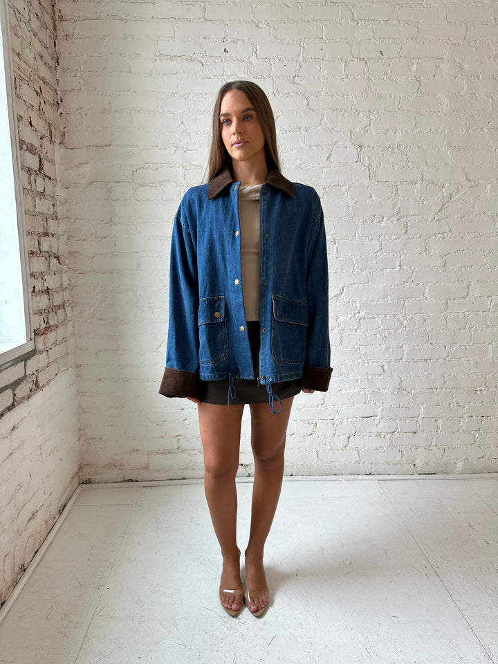 Woman wearing dark wash denim bomber jacket with brown corduroy collar and wrist cuffs.